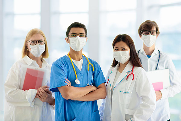 Portrait of diverse medical staff wearing face masks, scrubs, and stethoscopes.