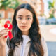 Young Hispanic woman holding a red ribbon in support of HIV/AIDs awareness.